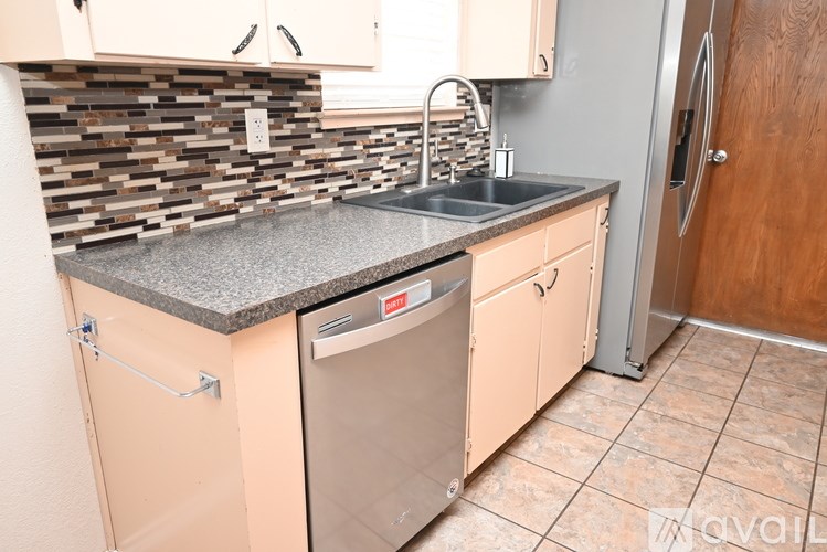 A kitchen with a stone backsplash and a dishwasher.