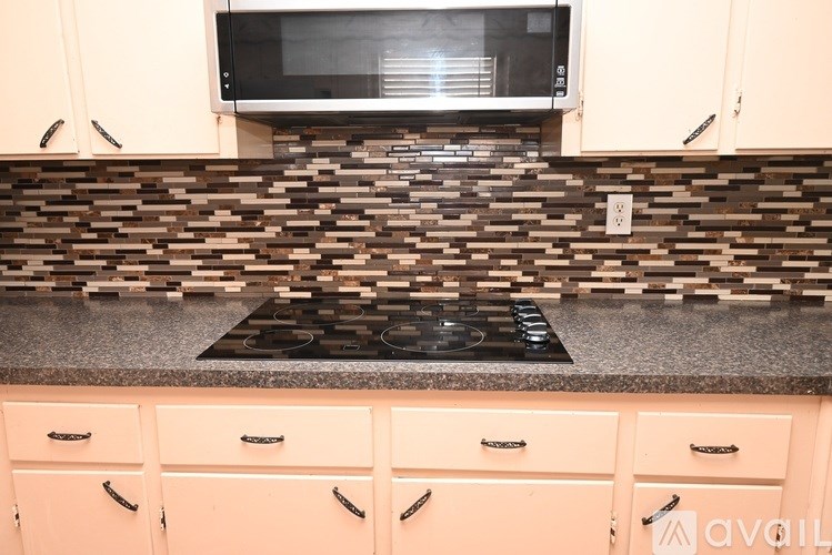 A kitchen with a black stove top oven and a microwave above it.
