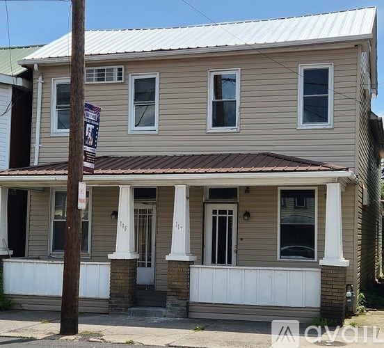 A two-story house with a porch and a white fence.
