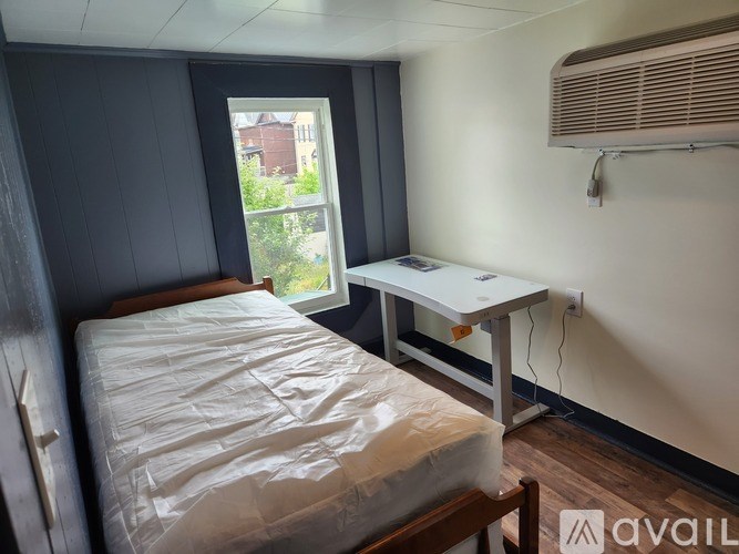 A bedroom with a bed, desk, and window.