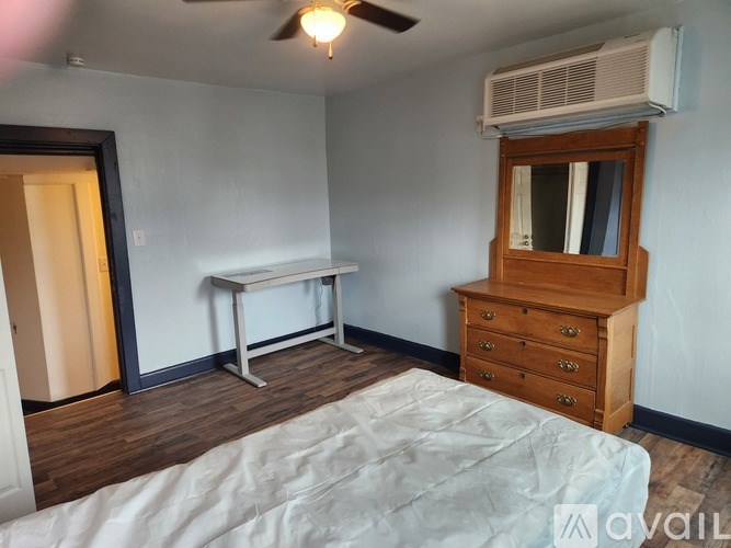 A bedroom with a bed, dresser, and window.