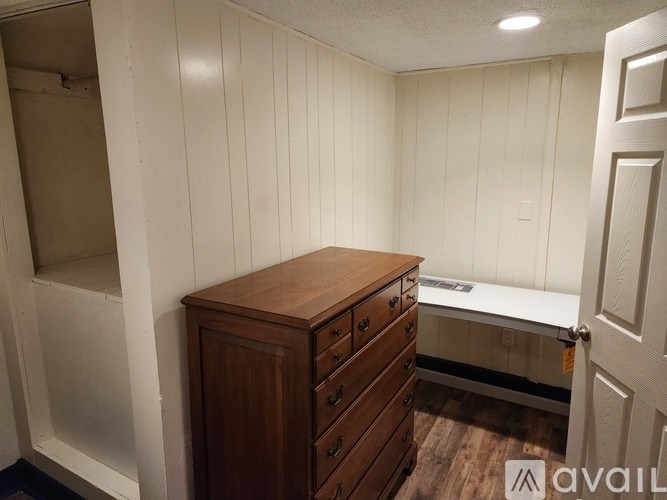 A wooden dresser sits in a room with white walls.