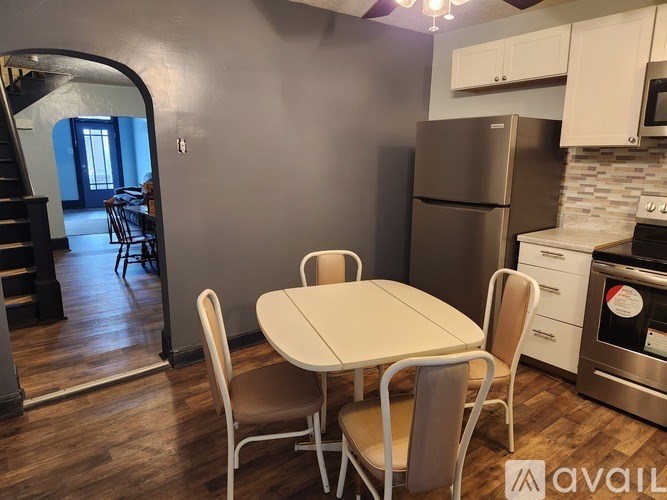 A kitchen with a table and chairs in the foreground and a staircase in the background.