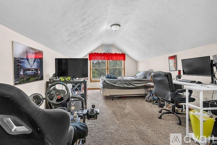 A room with a bed, desk, and gaming chair.