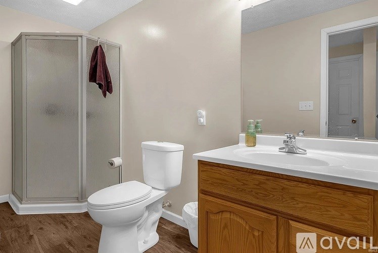 A bathroom with a toilet, sink, and shower stall.