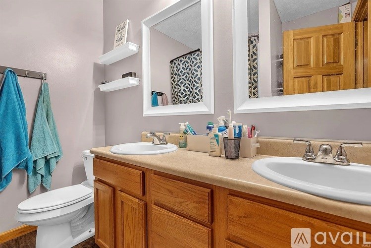A bathroom with a toilet, sink, mirror, and towel rack.