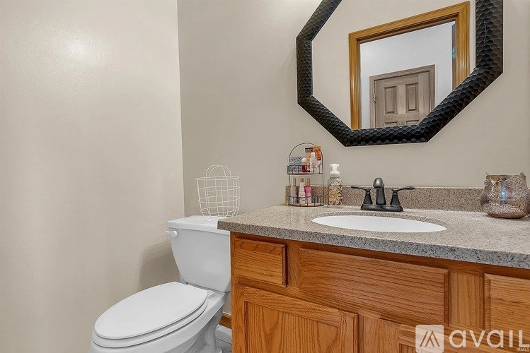 A bathroom with a toilet, sink, and mirror.