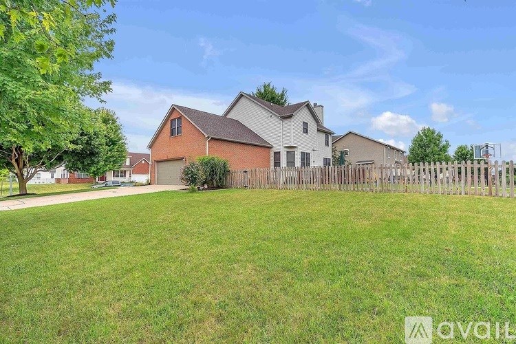 A house with a fence and a tree in front of it.