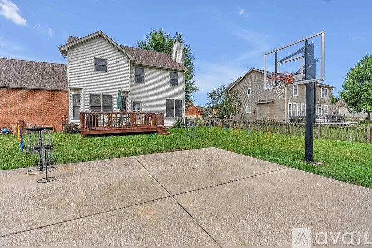 A basketball hoop is installed in a backyard with a concrete ground.