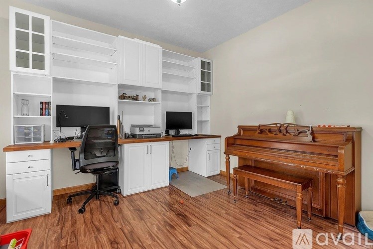 A room with a desk, chair, and a piano.