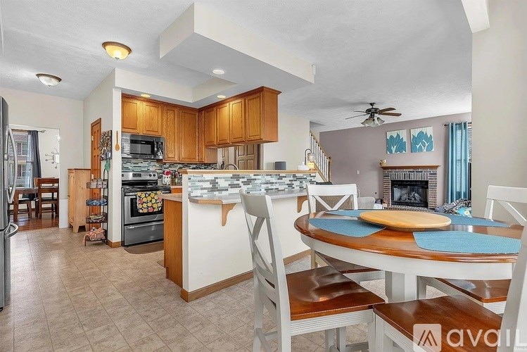 A kitchen with a table and chairs in front of a fireplace.