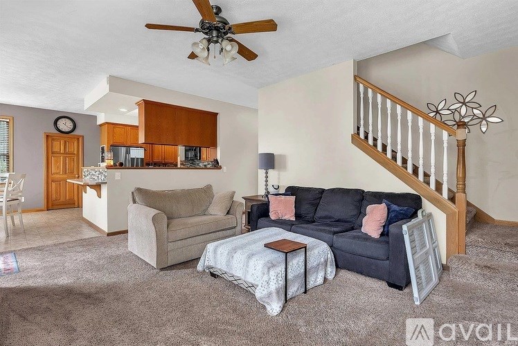 A living room with a couch, chair, and a fan.