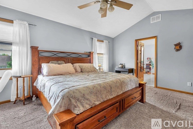 A bedroom with a large bed and a ceiling fan.