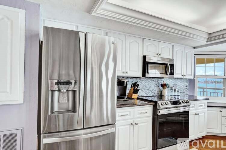 A kitchen with a stainless steel refrigerator and white cabinets.