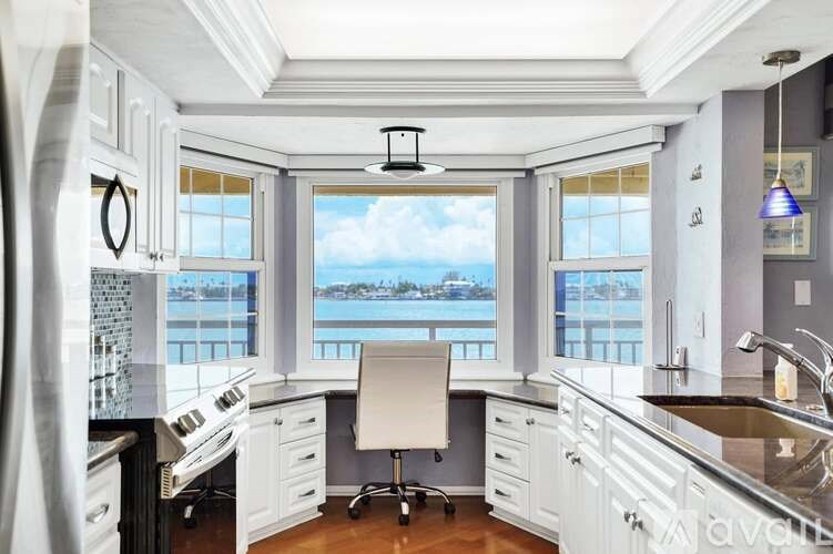 A kitchen with a view of the water outside the window.