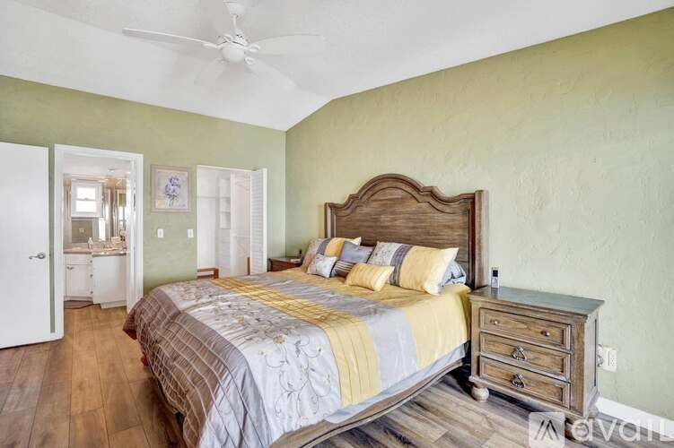 A bedroom with a bed, dresser, and a ceiling fan.