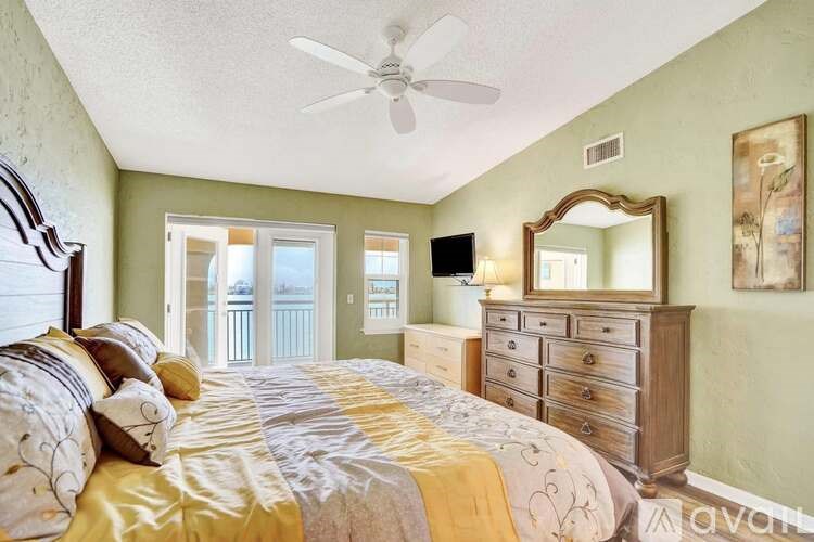A bedroom with a bed, dresser, mirror, and a ceiling fan.