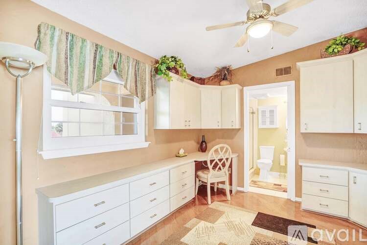 A kitchen with white cabinets and a ceiling fan.