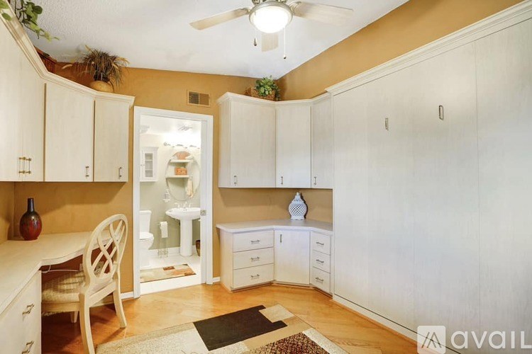 A kitchen with white cabinets and a wooden chair.