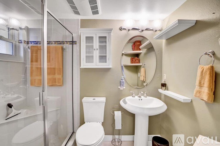 A small bathroom with a toilet, sink, and shower.