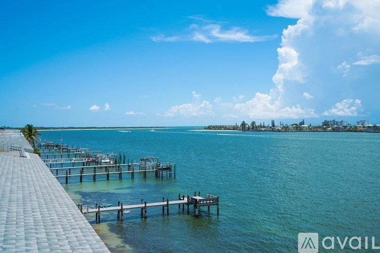 A pier extends into a calm body of water with a clear blue sky above.