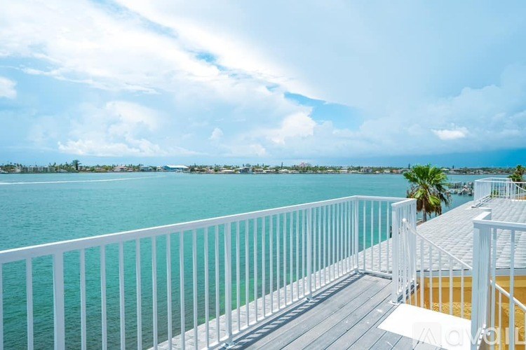 A balcony overlooks a body of water with a clear sky above.