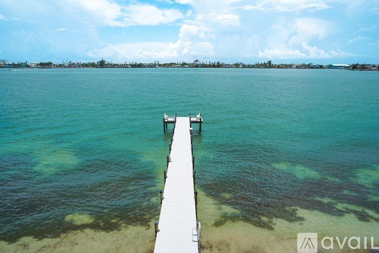 A wooden pier extends into a beautiful blue sea.