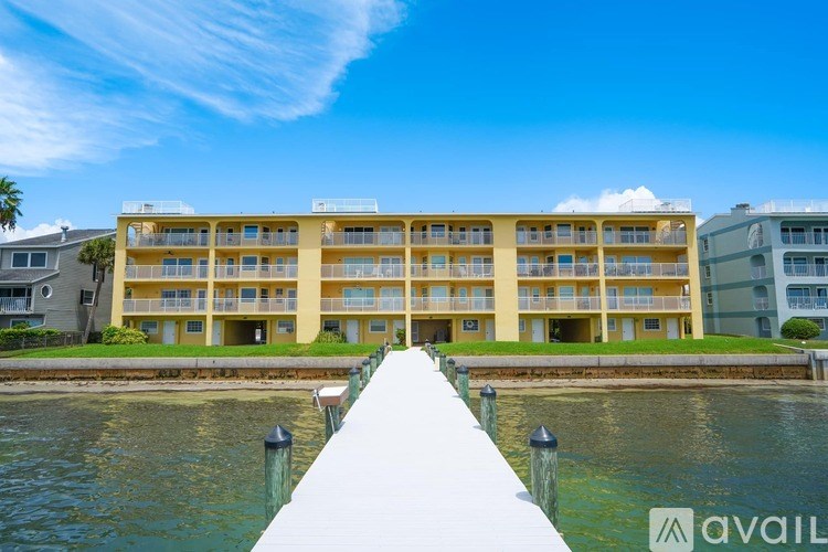 A large yellow building with a white roof is situated next to a body of water.