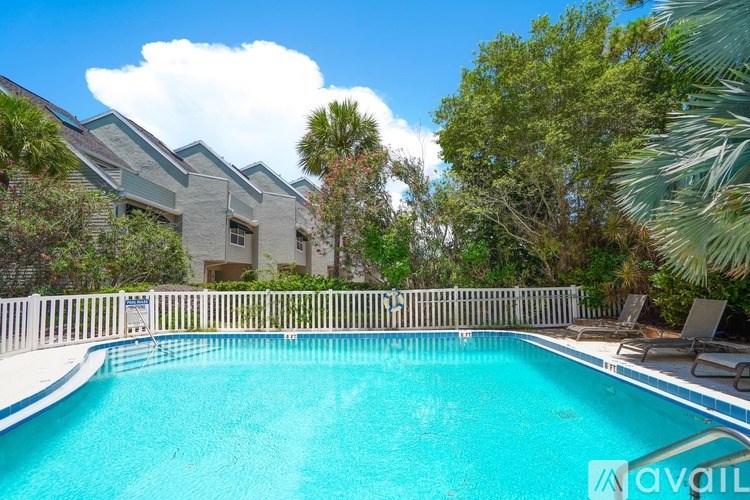 A swimming pool in a backyard with a house and trees in the background.