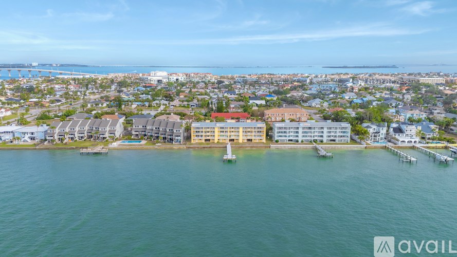 A bird's eye view of a coastal town with a large body of water in the foreground and buildings scattered throughout the landscape.
