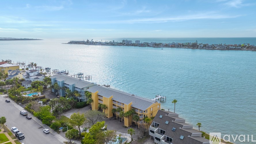 A bird's eye view of a coastal area with buildings, cars, and a body of water.