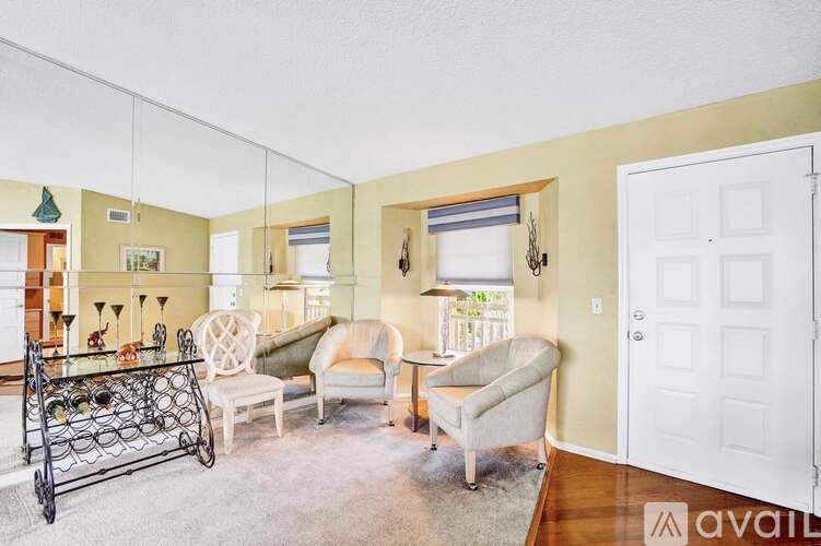 A living room with a black wrought iron table and white chairs.