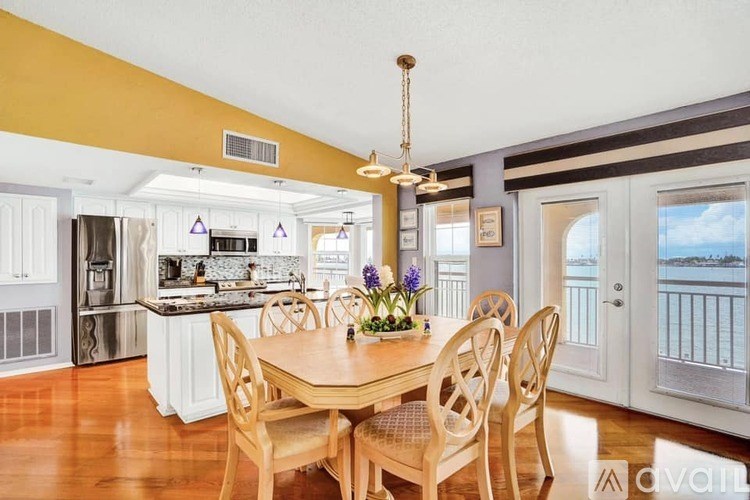 A dining room with a table set for four and a view of the water outside.