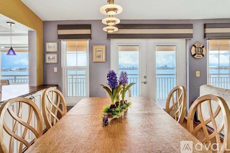 A wooden dining table with a vase of flowers on it and chairs around it.