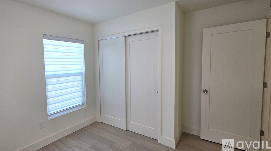 A room with a window, two doors, and a wall.