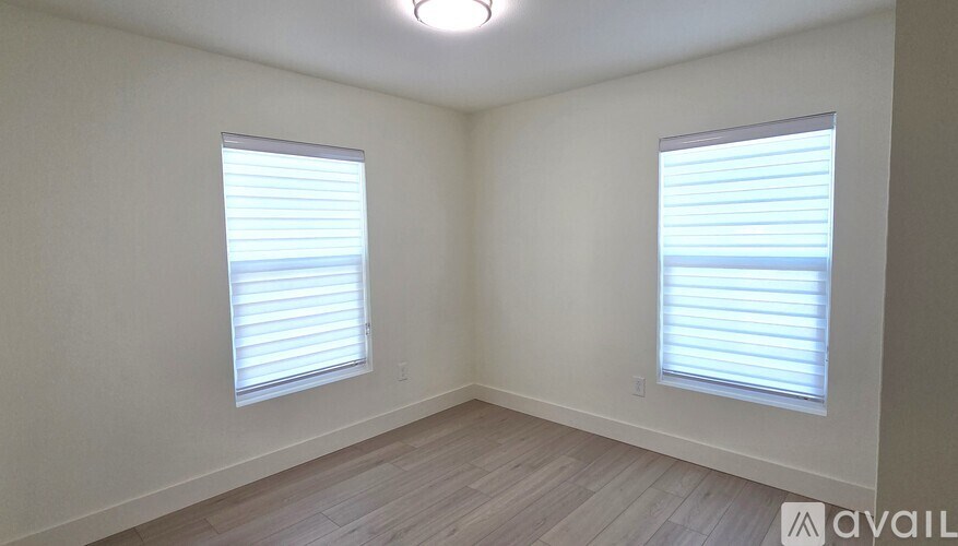 A room with two windows and a wooden floor.