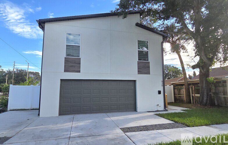 A white house with a black garage door is for sale.