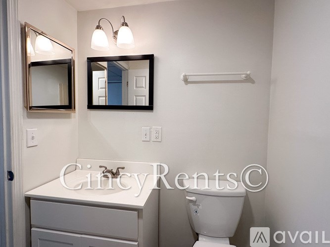 A bathroom with a toilet, sink, and mirror.