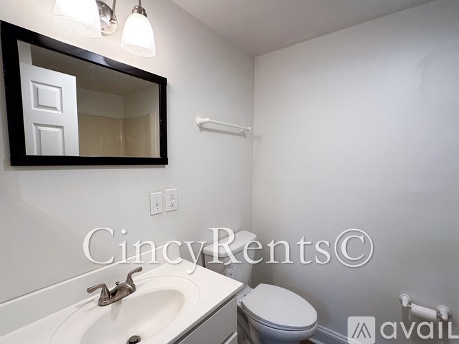 A bathroom with a sink, toilet, and mirror.