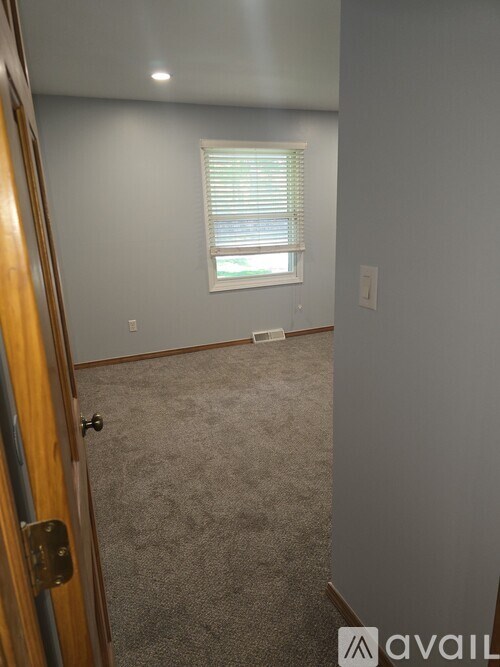 A room with a carpeted floor and a window with blinds.