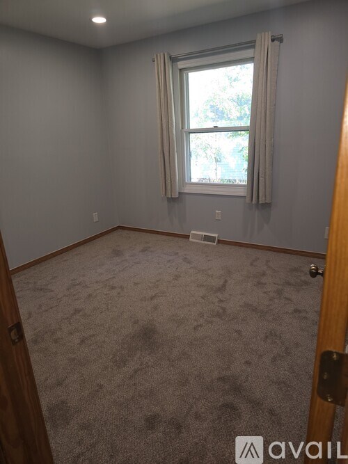 A room with a carpeted floor and a window with curtains.