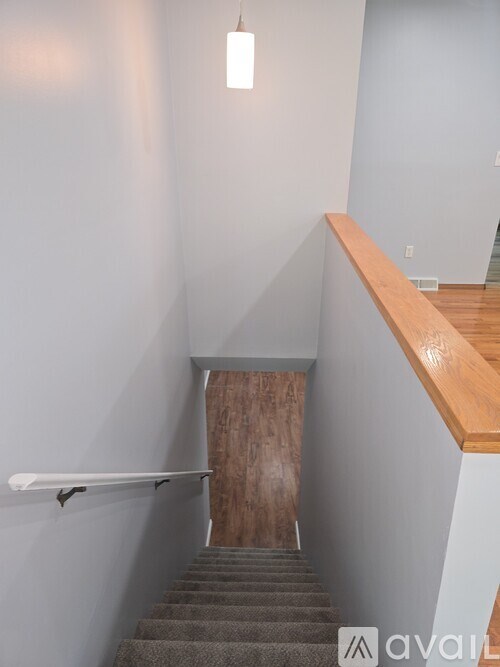 A staircase with a wooden handrail and a light hanging from the ceiling.