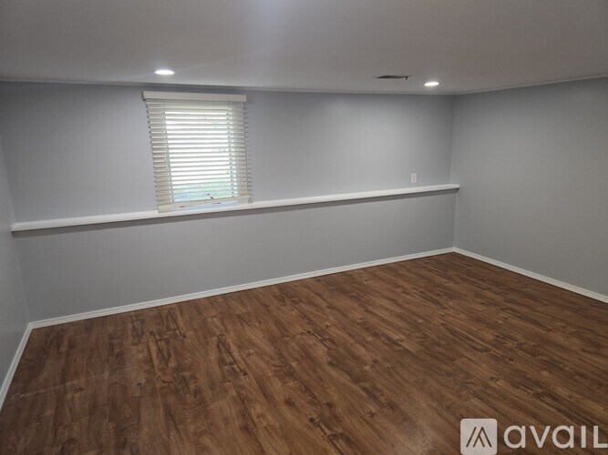 A room with wooden flooring and a window with blinds.