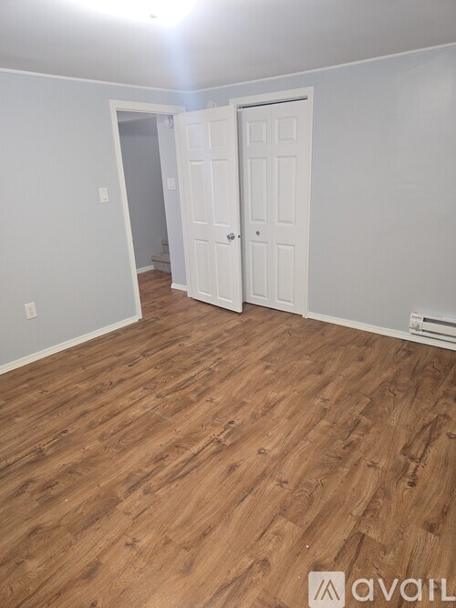 A room with a white door and a wooden floor.