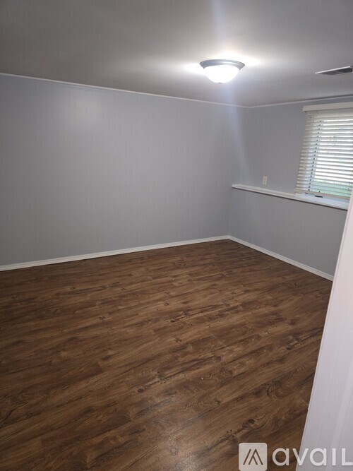 A room with wooden flooring and a window with blinds.