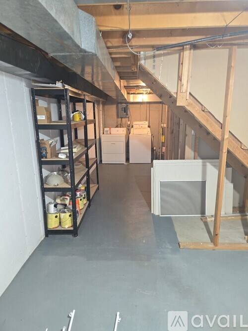 A room under construction with a refrigerator and a shelf with various items.