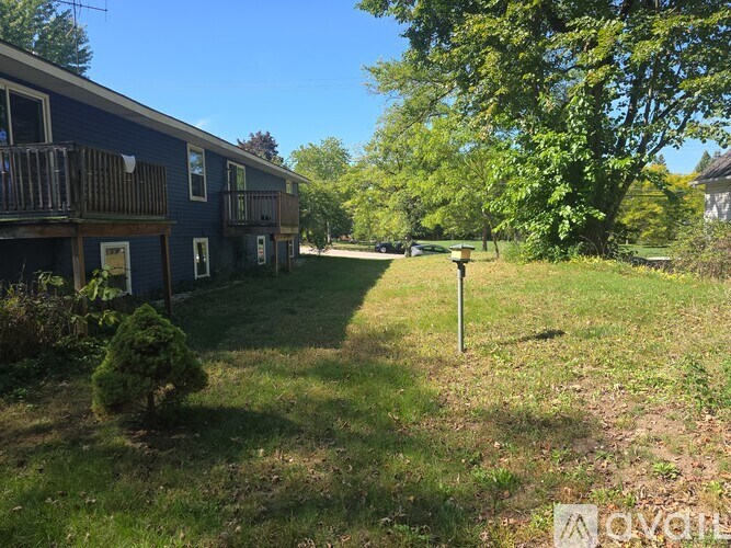 A grassy area with a building and trees in the background.