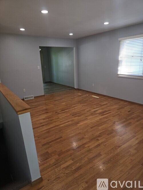 A room with wooden flooring and a window with blinds.