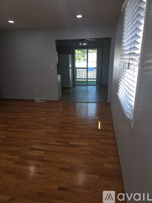 A room with wooden flooring and a window with blinds.