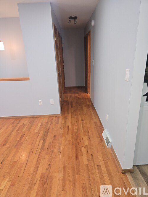 A hallway with wood flooring and white walls.
